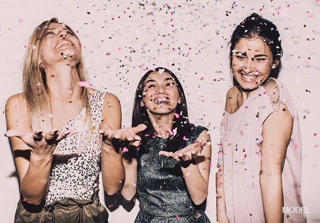 A group of woman smiling and holding out hands trying to catch confetti