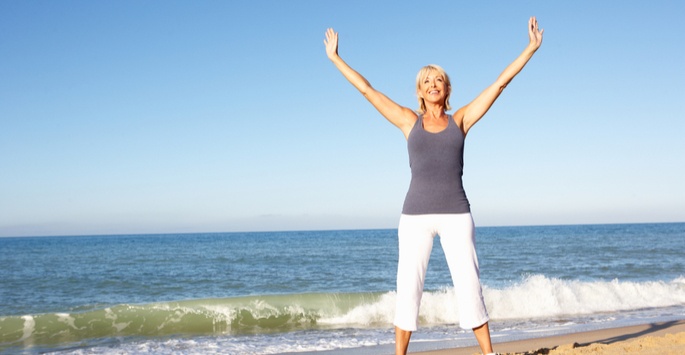 woman on beach lifting arms